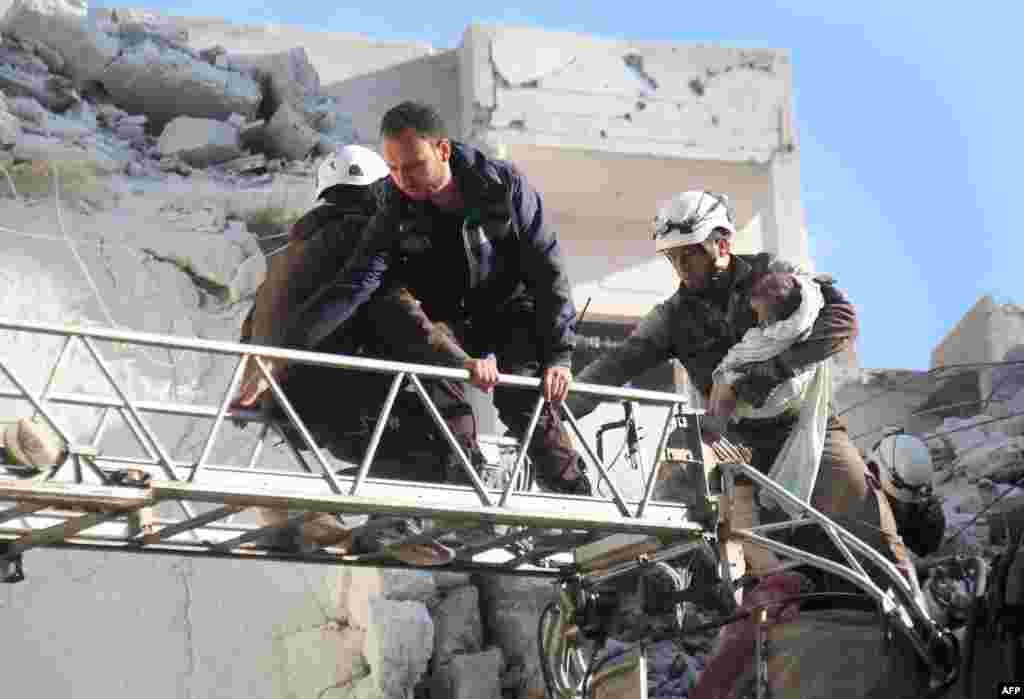 Syrian Civil Defense members evacuate a toddler from the rubble of buildings destroyed following Russian air strikes on May 30, 2016, on the northwestern city of Idlib.