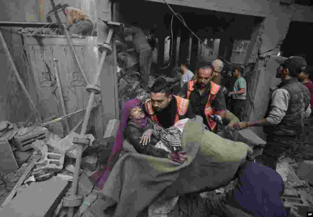 Palestinian rescuers evacuate an injured woman that was found under the rubble of a destroyed house following an Israeli airstrike in Khan Younis refugee camp, southern Gaza Strip, Nov. 18, 2023. 