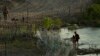 A Texas state trooper watches as young migrants walk along concertina wire on the banks of the Rio Grande as they try to enter the U.S. from Mexico in Eagle Pass, Texas, July 6, 2023. 