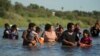 FILE - Migrants navigate around concertina wire along the banks of the Rio Grande after crossing from Mexico into the U.S., Aug. 1, 2023, in Eagle Pass, Texas. 