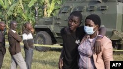 Mwanafunzi asaidiwa na mzazi kwenye shule iliyoshambuliwa na wanamgambo wa ADF huko Mpondwe, Uganda. 