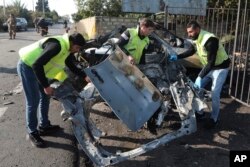 Sejumla pekerja membersihkan puing-puing mobil yang hancur di Kota Bazouriyeh, Lebanon, Sabtu, 20 Januari 2024. Serangan drone Israel terhadap mobil di dekat kota pelabuhan Tire di Lebanon menewaskan dua orang. (Foto: Mohammad Zaatari/AP Photo)