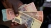 FILE - A currency trader holds worthless Zimbabwean dollar notes on the streets of Harare, Zimbabwe, June, 9, 2022.