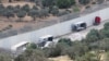 Truk-truk yang membawa bantuan ke Gaza terhenti setelah dirusak oleh para pemukim Israel dekat pos pemeriksaan tak jauh dari Hebron di Tepi Barat yang diduduki Israel, Selasa, 14 Mei 2024. (Foto: Mussa Qawasma/Reuters)