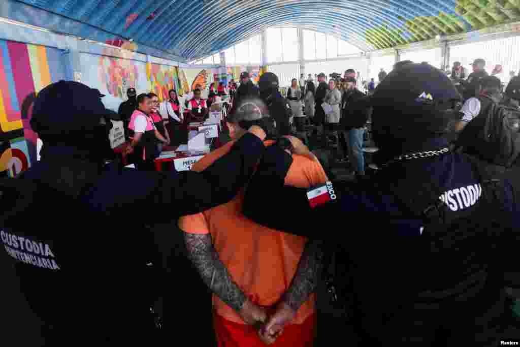 Prison officers escort an inmate to vote during early voting for people in preventive detention at the Barrientos prison, ahead of the June 2 general election, in Tlalnepantla, Mexico, May 8, 2024. 