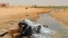 Un migrant d'origine africaine boit de l'eau à son arrivée dans une zone inhabitée près d'al-Assah à la frontière libyo-tunisienne le 30 juillet 2023.