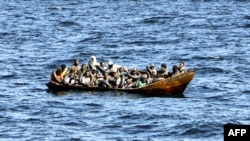 FILE - Para migran asal Afrika yang mencoba melarikan diri ke Eropa berdesakan di perahu kecil, saat penjaga pantai Tunisia bersiap untuk memindahkan mereka ke kapal mereka, di laut antara Tunisia dan Italia, 10 Agustus 2023. (FETHI BELAID / AFP)