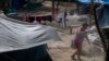 A migrant sweeps the ground at a shelter encampment in the border town of Matamoros, Mexico, Aug. 16, 2023. 