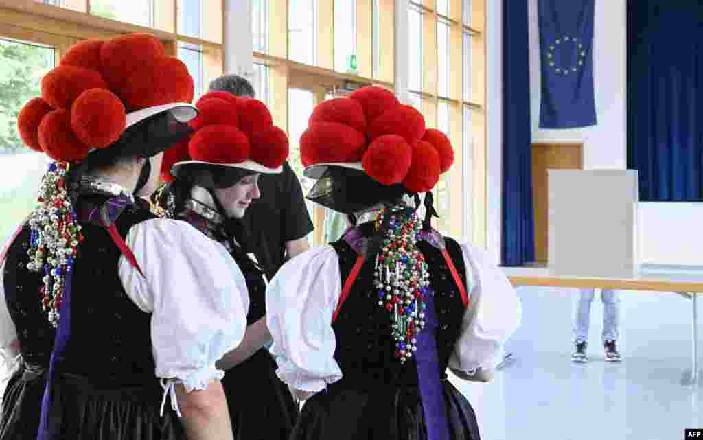 Women wearing traditional &quot;Bollenhut&quot; pompon hats, typical for the Black Forest region, line up to fill out their ballot papers for European Parliament Elections at a polling station in Gutach, southern Germany.
