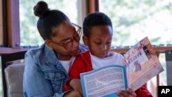 Adriane Burnett reads to her son Karter Robinson in Birmingham, Alabama, April 14, 2024.
