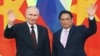 In this pool photograph distributed by the Russian state agency Sputnik, Russia's President Vladimir Putin (L) and Vietnam's Prime Minister Pham Minh Chinh (R) wave as they pose for photos at the Government Office in Hanoi, on June 20, 2024.