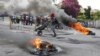 A man pushes a wheelbarrow past burning tires during a protest demanding the resignation of Prime Minister Ariel Henry in Port-au-Prince, Haiti, March 7, 2024.