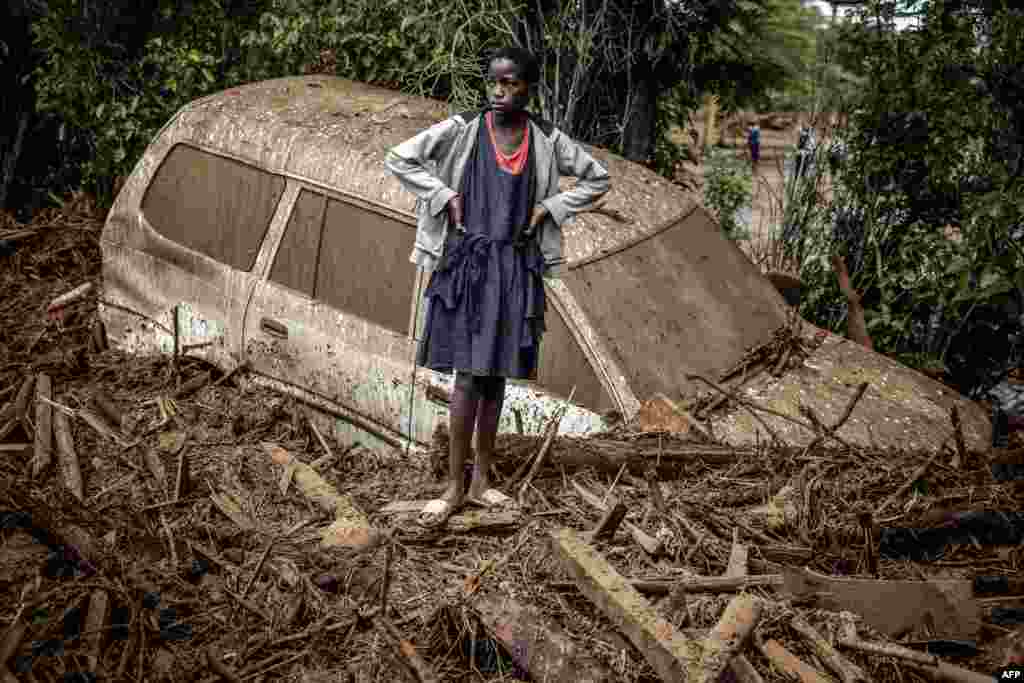 A girl looks on next to a damaged car buried in mud in an area heavily affected by torrential rains and flash floods in the village of Kamuchiri, near Mai Mahiu, Kenya.&nbsp;At least 45 people died when a dam burst its banks near a town in Rift Valley, police said, as torrential rains and floods battered the country.&nbsp;