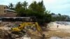 A tourist stands next to a tractor clearing an area after thirteen people, including a Russian couple, died in a mudslide on the Thai resort island of Phuket, Thailand, Aug. 25, 2024. 
