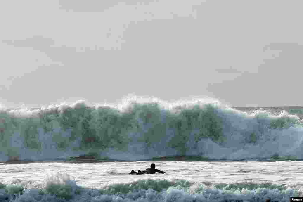 A surfer tries to navigate through a rough sea during Storm Ciaran, in Tramore, Ireland.