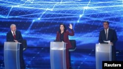 Simone Tebet, kandidat dalam pemilihan presiden Brazil, mengangkat tangannya di tengah sesi debat capres yang diikuti oleh Presiden Jair Bolsonaro (kanan), dan kandidat lainnya Luiz Inacio Lula da Silva, di Sao Paulo, Brazil, pada 28 Agustus 2022. (Foto: Reuters/Carla Carniel)
