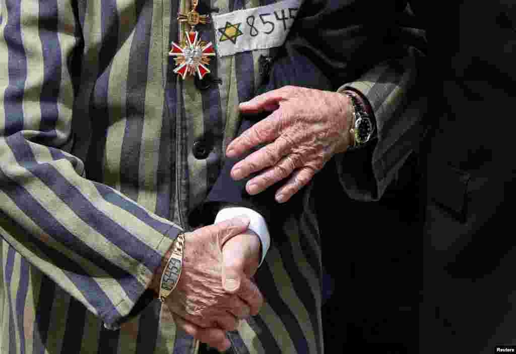 Polish President Andrzej Duda and Holocaust survivor Edward Mosberg hold hands as they walk in front of the "Death Wall" during the annual International "March of the Living" through the grounds of the former Auschwitz death camp, in Oswiecim, Poland.