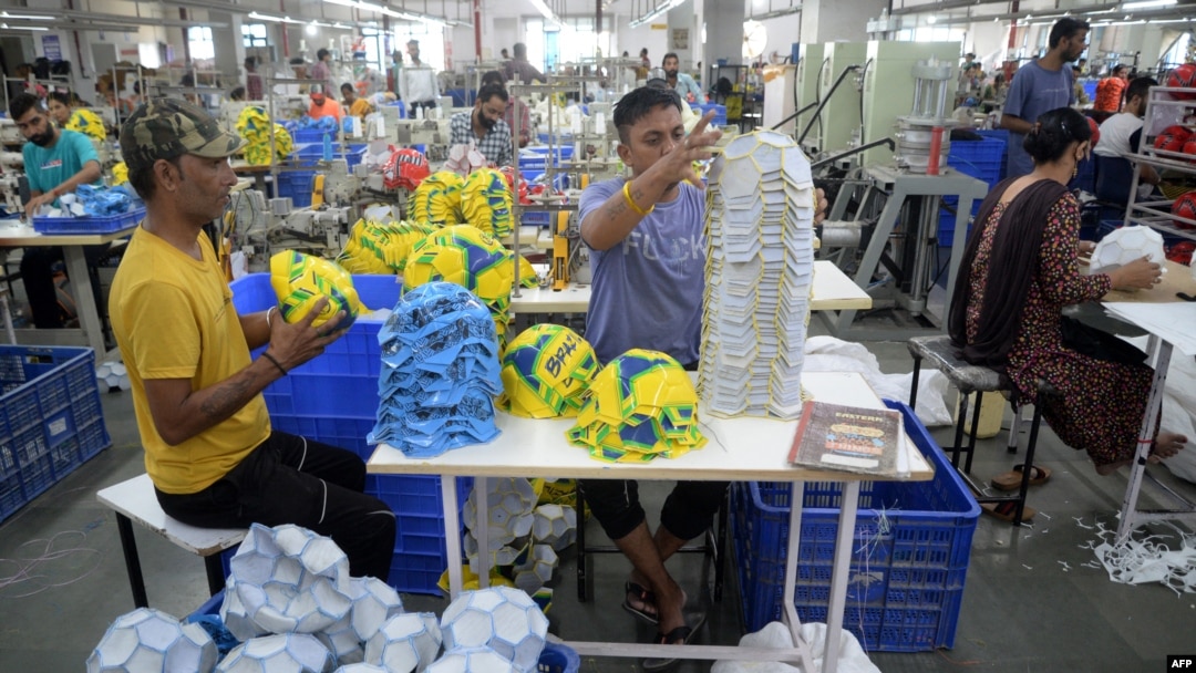 FILE - Factory workers prepare to stitch soccer balls at a manufacturing unit in Jalandhar in India's Punjab state on Aug. 22, 2022.