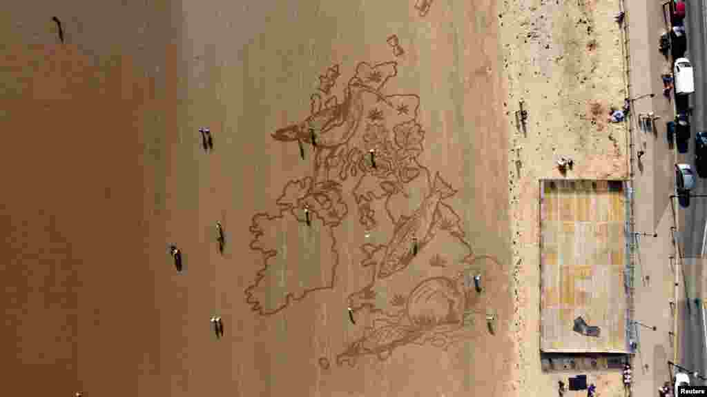 People walk past a huge sand drawing on South Bay Beach, created by Sand in Your Eyes, to alert&nbsp; people to the loss of wildlife, in Scarborough, Britain, March 23, 2022.