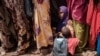 Seorang wanita menggendong anaknya saat menunggu pembagian makanan bergizi tinggi dan konsultasi medis di kamp Tawkal 2 Dinsoor di Baidoa, Somalia, 14 Februari 2022. (Foto: AFP