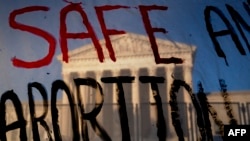 Gedung Mahkamah Agung AS terlihat di balik poster bertuliskan "selamatkan Aborsi" di Washington, DC, pada 10 Mei 2022. (Foto: AFP/Stefani Reynolds)