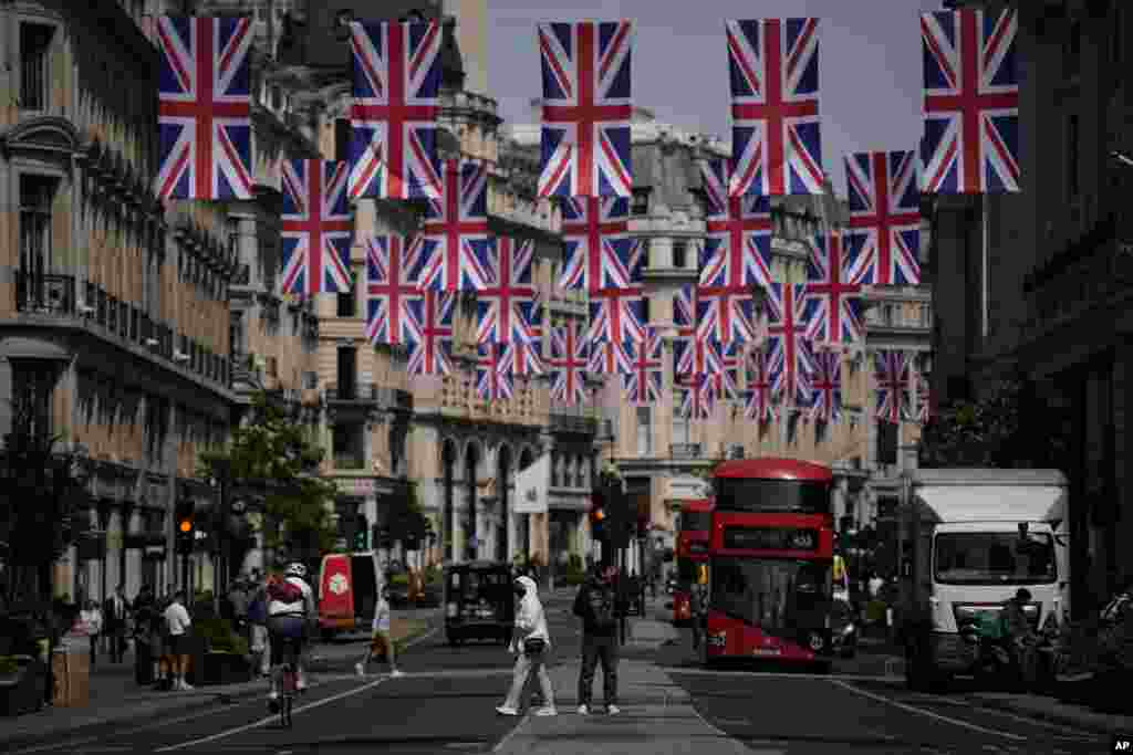 People cross the Regent Street shopping district with Union flags hanging over it to mark the upcoming Platinum Jubilee of the 70 year reign of Britain&#39;s Queen Elizabeth II, in London.