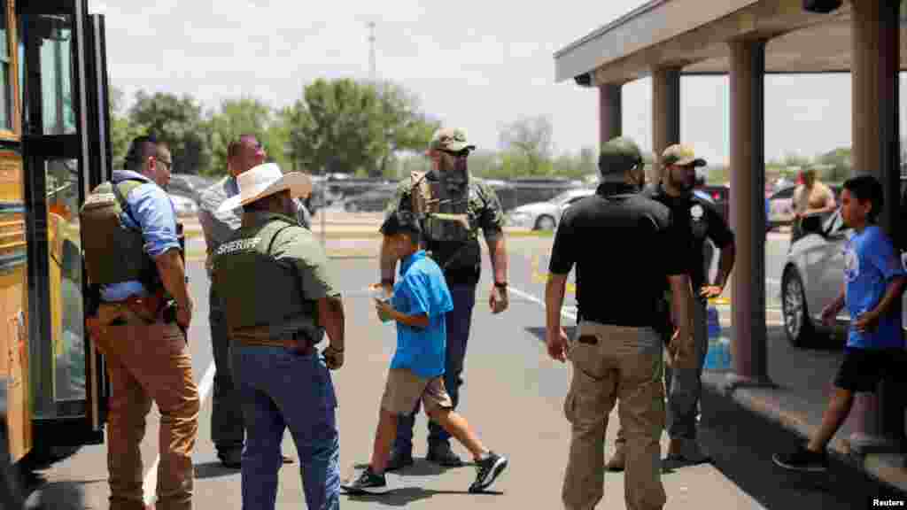 Watoto wakingia kwenye basi ya shule wakilindwa wa maafisawa usalama baada ya shambulio katika shule yao ya Robb Elementary mjini Uvalde, Texas, May 24, 2022.