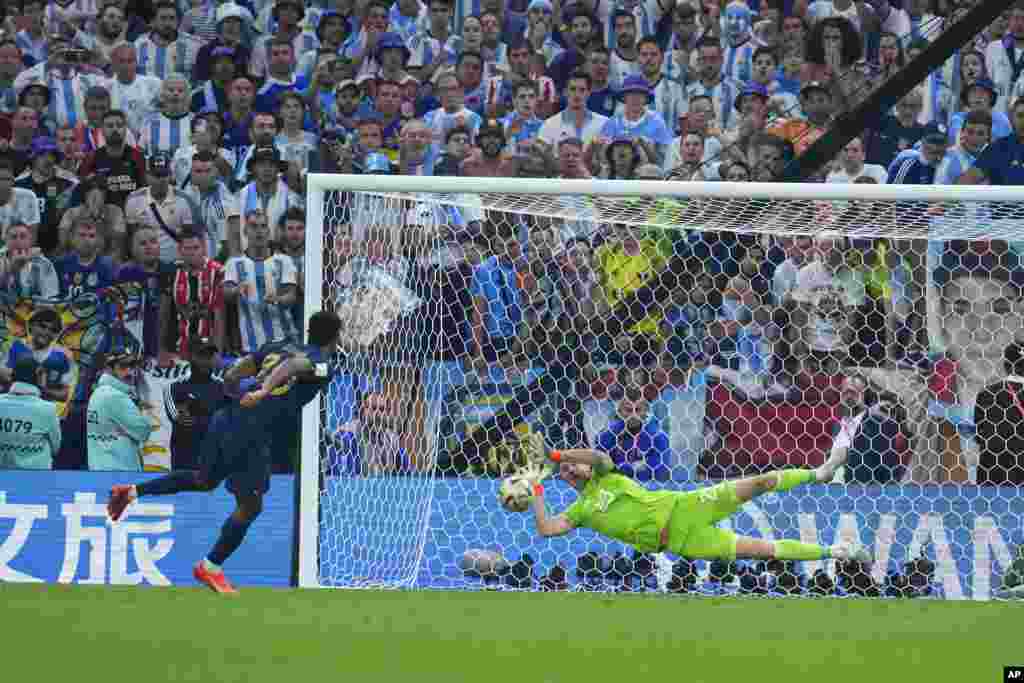 Argentina&#39;s goalkeeper Emiliano Martinez blocks a shot from France&#39;s Kingsley Coman in a penalty shootout during the World Cup final soccer match between Argentina and France at the Lusail Stadium in Lusail, Qatar.