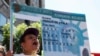 FILE - A woman holds an enlarged replica of a green card during a rally to demand immigration reform, in Los Angeles, Oct. 5, 2013.