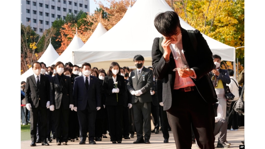 A mourner wipes his tear as he pays a silent tribute for victims of a deadly accident following Saturday night's Halloween festivities, at a joint memorial altar for victims at Seoul Square in Seoul, South Korea, Monday, Oct. 31, 2022. (AP Photo/Ahn Young