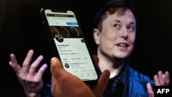 Layar ponsel menampilkan akun Twitter Elon Musk dengan foto dirinya di latar belakang, pada 14 April 2022, (Foto: AFP)