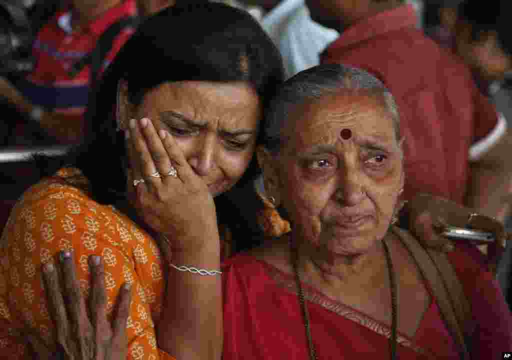 Seorang perempuan India menangis saat kerabatnya (kanan) yang sedang berziarah di Nepal saat gempa terjadi Sabtu, kembali ke bandar udara di Ahmadabad, India (27/4). (AP/Ajit Solanki)