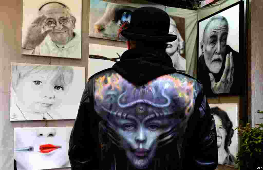 Italian artist Frans looks at his work in the Via Margutta, a small Roman street renowned for inspiring the works of sculptors, painters, poets and film directors, during the annual exhibition “100 Painters on Via Margutta” in Rome.