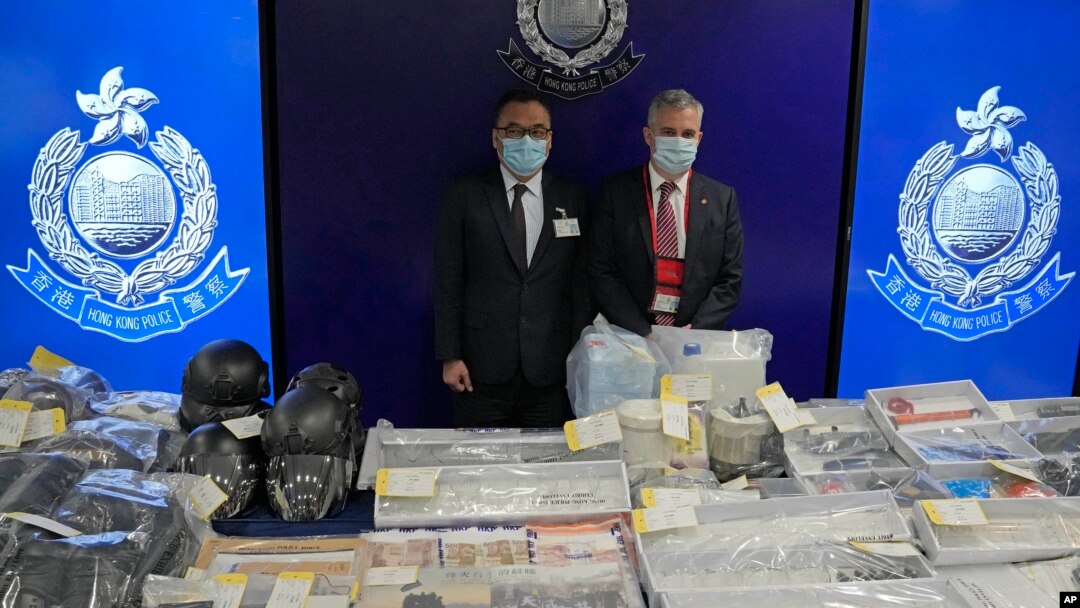 Senior Superintendent Li Kwai-wah, left, of Hong Kong Police, and senior bomb disposal officer Alick McWhirter pose with the seized evidence during a news conference at police headquarters in Hong Kong, July 6, 2021.(AP Photo/Kin Cheung)