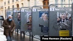 Un homme passe devant des affiches de campagne déchirées près d'un bureau de vote, à Paris, France, le 10 avril 2022. 