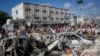 People walk amidst destruction at the scene of a double car bombing at a busy intersection, a day after the attack, in Mogadishu, Somalia, Oct. 30, 2022.