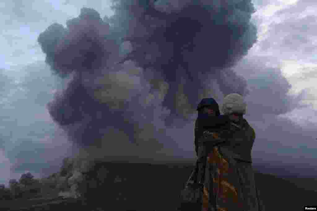A mother holds her son as they watch the eruption of Mount Sinabung at Berastepu village in Karo district, Indonesia's North Sumatra province. More than 22,000 villagers have been evacuated since authorities raised the alert status for the volcano to the highest level in November.