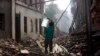 FILE - A Nepalese man carrying a water jar walks past damaged houses in Bhaktapur, Nepal, May 14, 2015. 