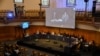 Witness Qelbinur Sidik, left on stage and left on screen above, give an evidential statement to the Panel of the independent Uyghur Tribunal during the first session of the hearings in London, June 4, 2021.