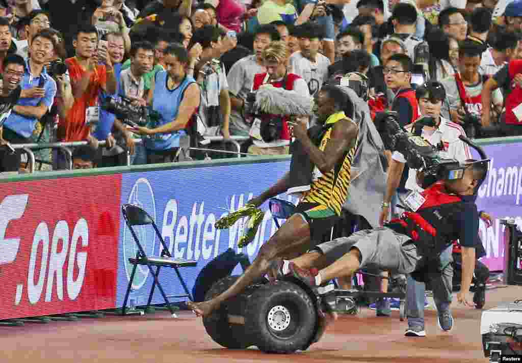 Usain Bolt of Jamaica is hit by a cameraman on a Segway as he celebrates after winning the men's 200 meters final at the 15th IAAF World Championships at the National Stadium in Beijing, China, Aug. 27, 2015.