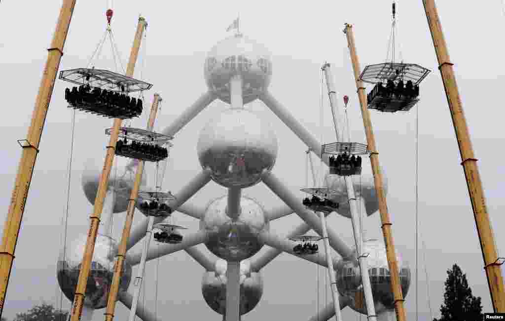 Ten tables, accommodating a total of 220 guests, are suspended from cranes at a height of 40 meters in front of the Atomium, a 102-meter (335 feet) high structure that includes nine spheres, built for the 1958 Brussels World's Fair, as part of the 10th anniversary of the event known as "Dinner in the Sky," in Brussels, Belgium.