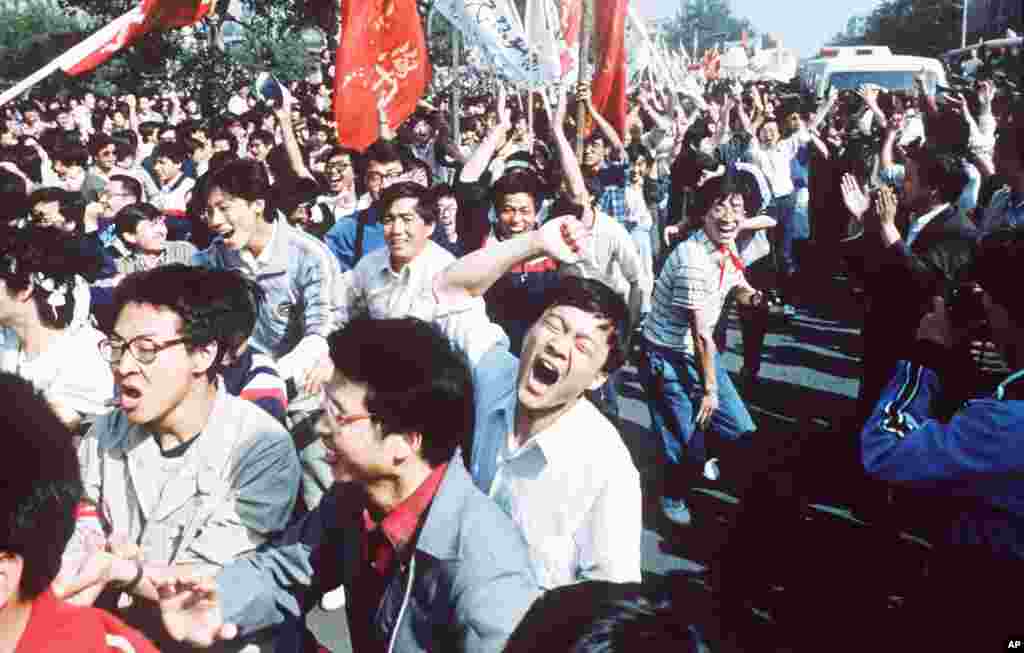 Para mahasiswa/i berseru setelah mendobrak blokade polisi dalam pawai pro-demokrasi ke Alun-alun Tiananmen di Beijing, 4 Mei 1989. (AP/S. Mikami)
