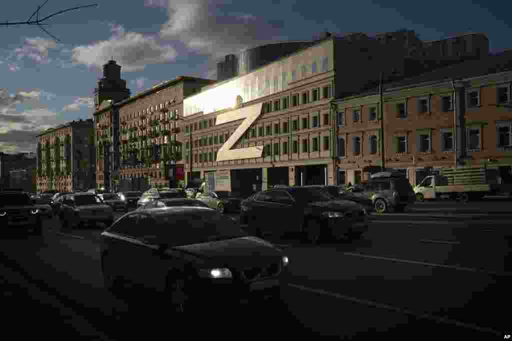 Cars drive along a street with a huge letter Z - which has become a symbol of the Russian military, and a hashtag reading "We don't abandon our own" - on a building during sunset in Moscow, Russia.