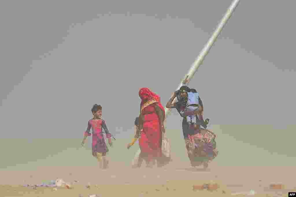 Women walk during a dust storm at the Sangam, the confluence of the Ganges, Yamuna and mythical Saraswati Rivers, in Allahabad, India.