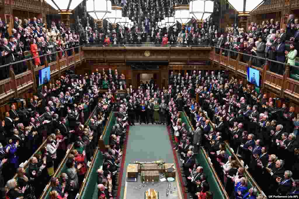 Ukrainian President Volodymyr Zelenskyy, on the screen, receives a standing ovation after he addresses British lawmakers by video link in the House of Commons in London. The Ukrainian leader urged Britain to increase sanctions on Russia, to recognize Russia as &ldquo;a terrorist country&rdquo; and to keep Ukraine&rsquo;s skies safe.