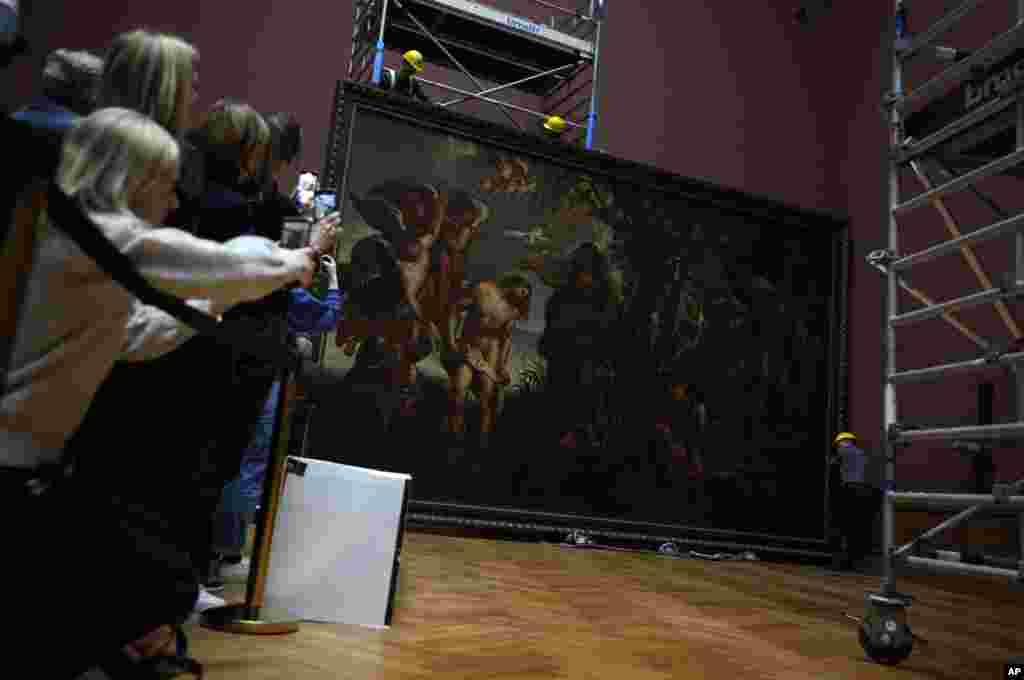 People take photos with their mobile phones as technicians and art handlers move the &quot;Baptism of Christ,&quot; by Baroque painter Peter Paul Rubens inside a gallery at the Royal Museum of Fine Arts Antwerp in Antwerp, Belgium.