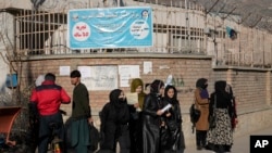 Wanafunzi wanawake wa Afghanistan wakisimama nje ya chuo kikuu cha mjini Kabul, Disemba 21, 2022.