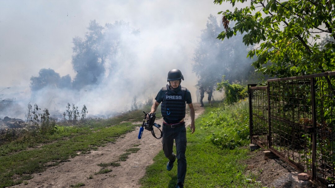 An AFP journalist runs as smoke rises behind after a bombardment in Bakhmut, Eastern Ukraine, July 31, 2022.