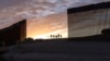 FILE - A pair of migrant families from Brazil pass through a gap in the border wall to reach the United States after crossing from Mexico to Yuma, Ariz., to seek asylum on June 10, 2021.