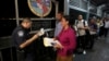 FILE - A U.S. Customs and Border Protection officer checks the documents of migrants who are on their way to apply for asylum in the United States, on International Bridge 1 as they depart Nuevo Laredo, Mexico, Sept. 17, 2019.